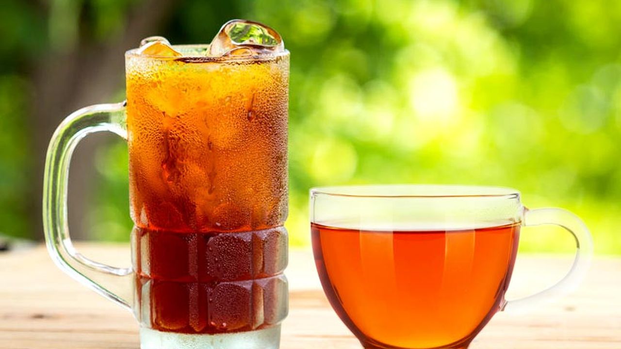 Gelas teh manis panas dan dingin dengan daun teh asli dan irisan lemon